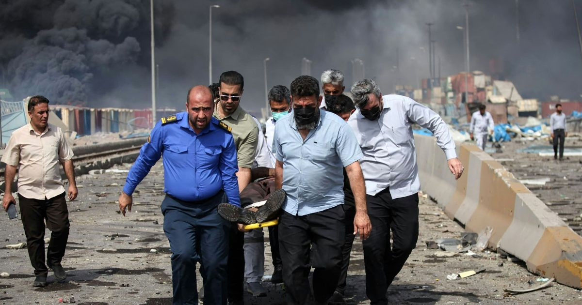 İnsanlar, 26 Nisan 2025'te İran'ın Hürmüzgan eyaletindeki Bender Abbas'ın güneybatısındaki Şahid Racei liman rıhtımında meydana gelen patlamanın ardından harap olmuş bulvar boyunca yaralı bir adamı taşıyor. Fotoğraf: AFP